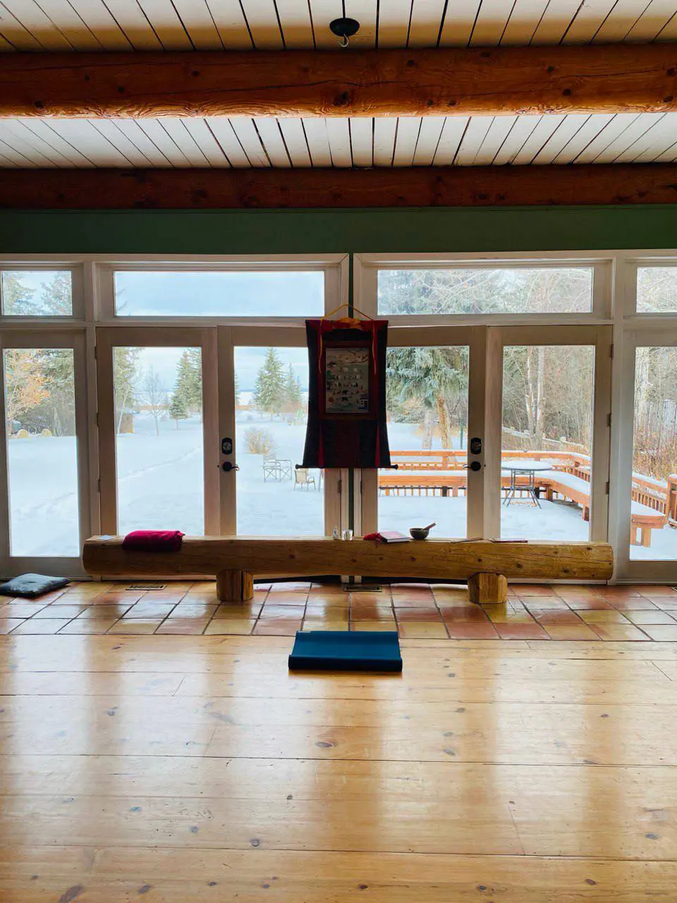 Vipassana retreat meditation hall with wooden floors and a view of the forest